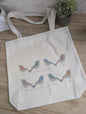 Tote bag with watercolor bird design on a wooden surface