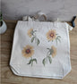 A beige cotton canvas tote bag with custom watercolor sunflower designs.